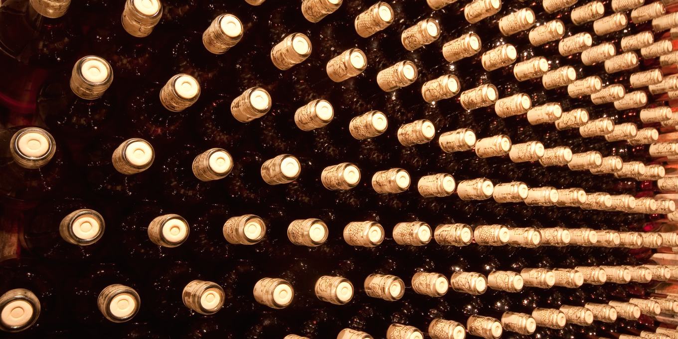 Rows of wine bottles lying in a rack, seen end on