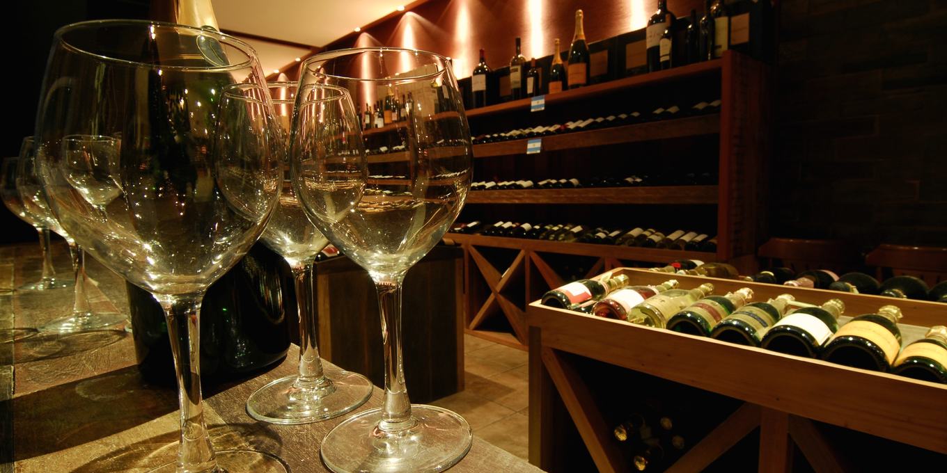 Empty wine glasses lined up on a bar in a cellar room